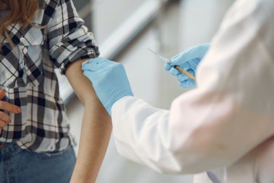 Woman receives vaccine from doctor wearing gloves
