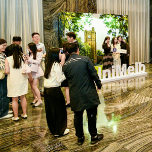 Small groups of alumni mingling at an event. Some are posing for a University-themed photo opportunity.
                                class=