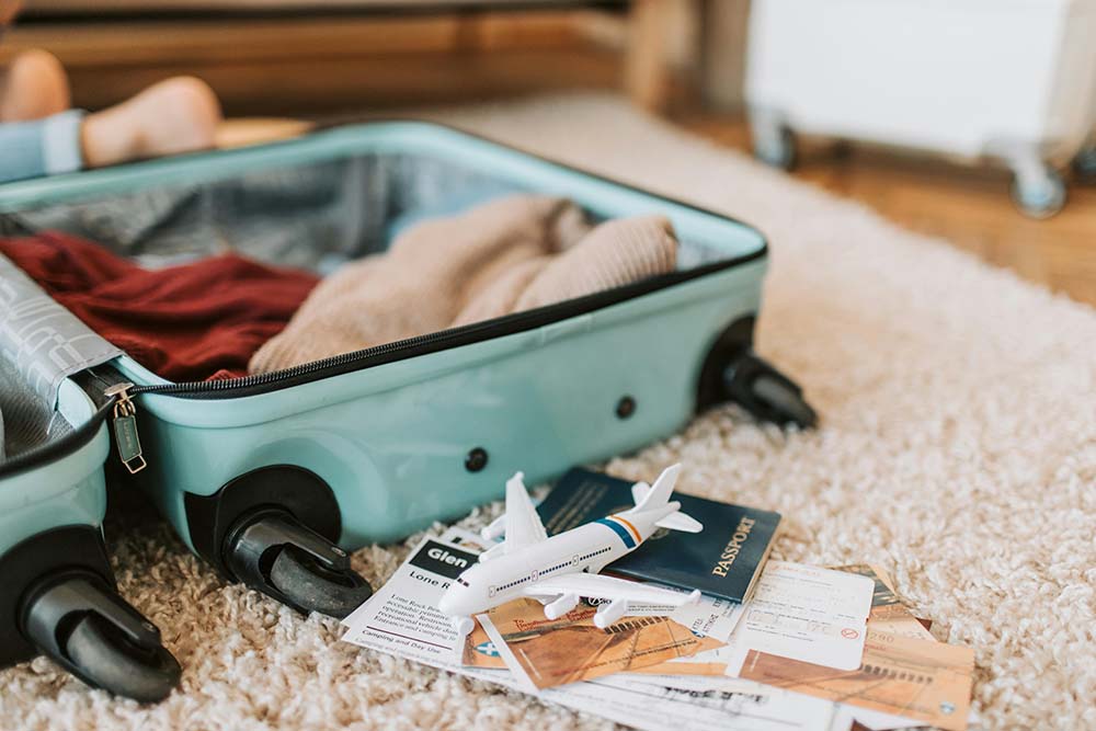 A scene of someone packing for a trip, with an open suitcase, passport, tickets, etc.