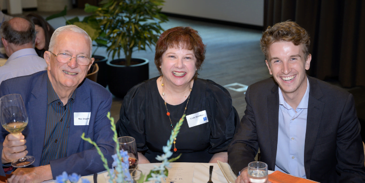 Attendees seated on a table at a Heritage Society event.