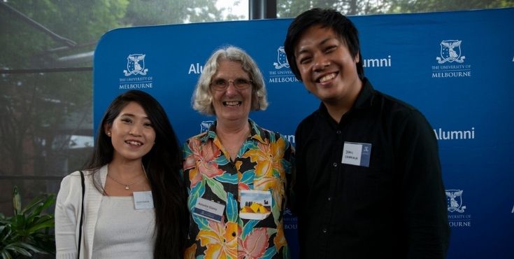 An alum with two students smiling