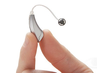 Fingers holding a hearing aid