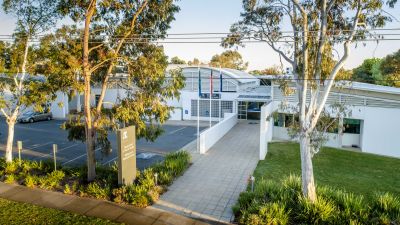 A modern white building with two gum trees out the front, showing signage with Department of Rural Health University of Melbourne 