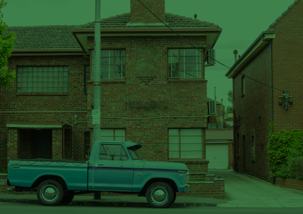 A tinted image of a house with an older pickup truck out the front.