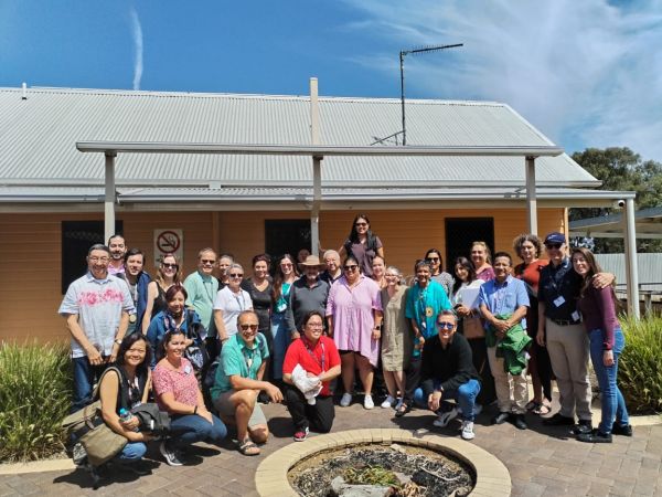 Group posing for a photo in front of small building.