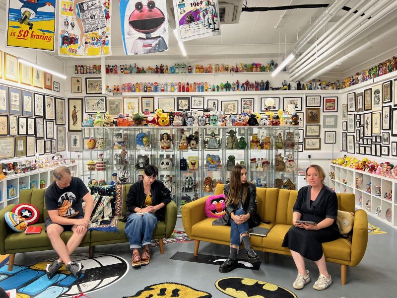 Four speaker on a couch surrounded by pop culture items.