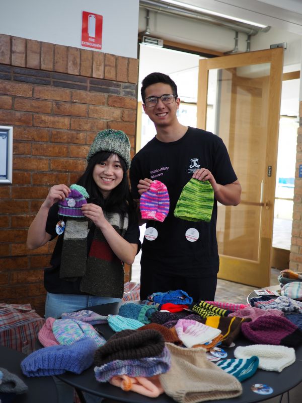 Two Sustainability Volunteers holding handmade woollen hats
