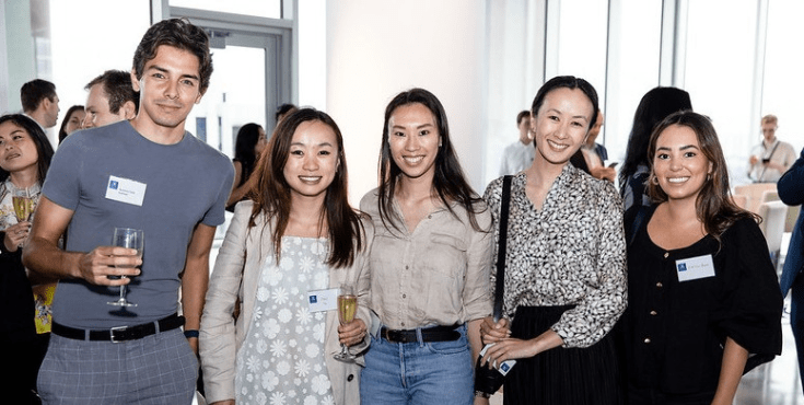 A group of five alumni smiling to camera with drinks in hand at a Latin America Network event.