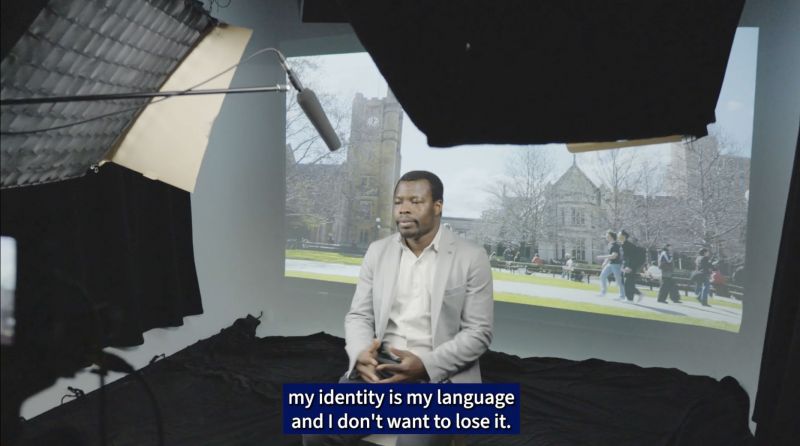 A man sits in a studio - the captions say 'my identity is my language and I don't want to lose it'.