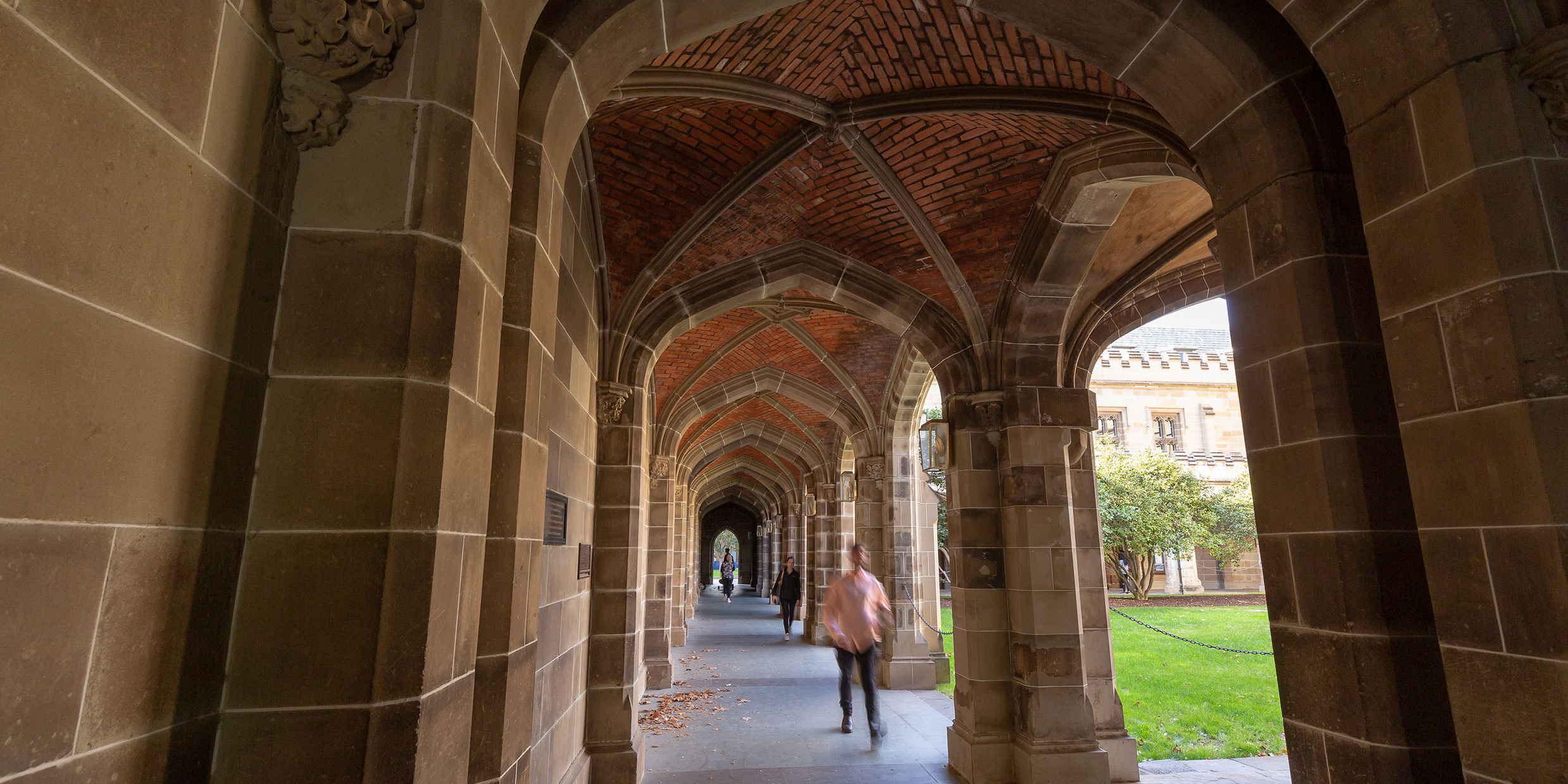 A person walks under a vaulted stone walkway