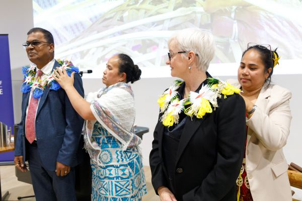 Two women fixing Rotuman garlands on a man and woman.