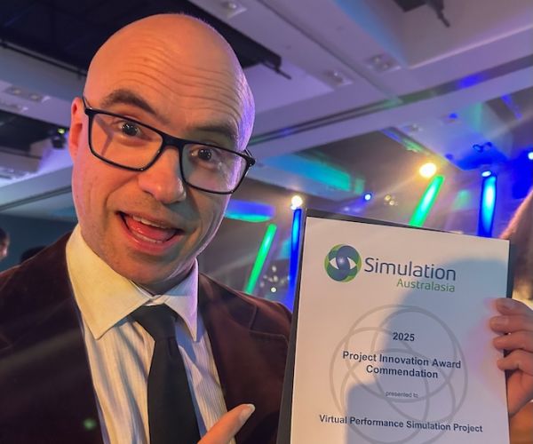 A man with an excited expression points at a certificate for an award 