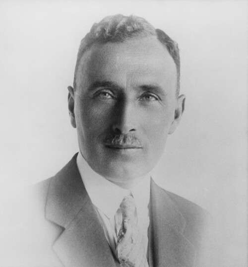 A black and white photograph of a man wearing a suit.