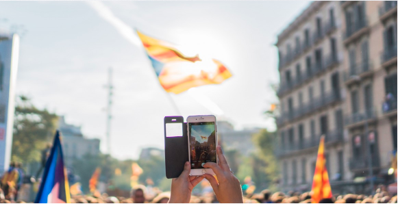 Image of a person's hand holding up a phone during a protest.