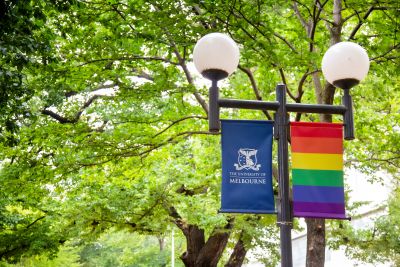 Image of rainbow Pride flag along side University of Melbourne banner.