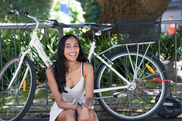 Woman smiling, sitting in front of bike