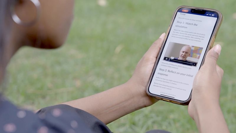 A young woman holds a phone with the learning activity on the screen.