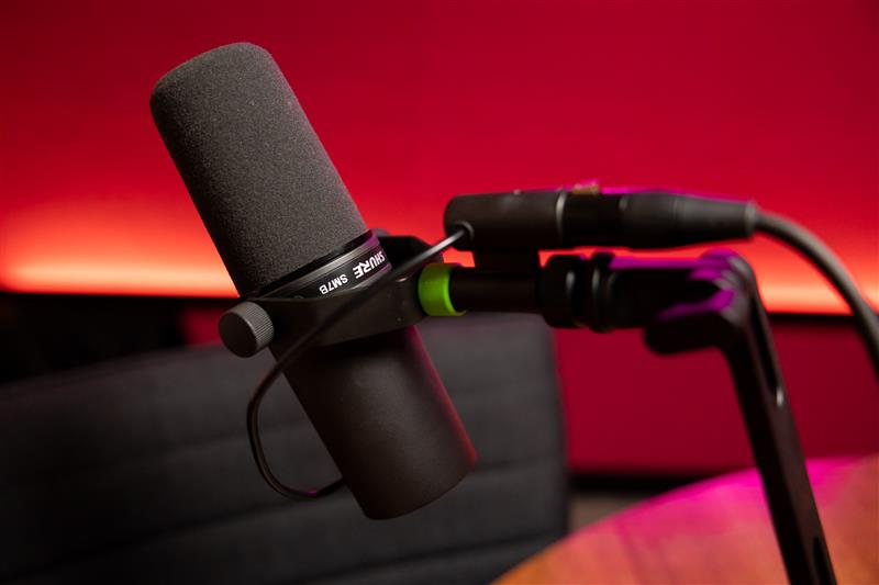 A close-up of a microphone in a studio with red lighting.
