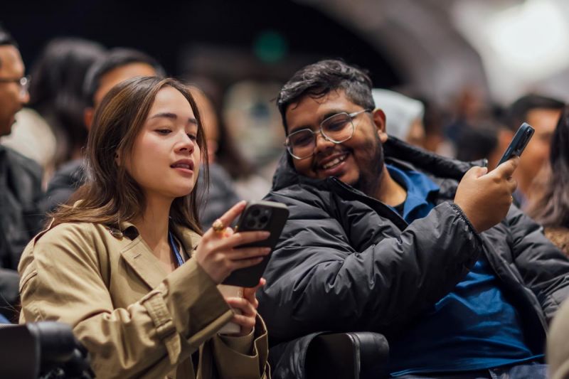Photo of two students using their mobile phones in a lecture theatre