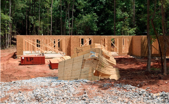 Image of a building under construction beside a wooded area.