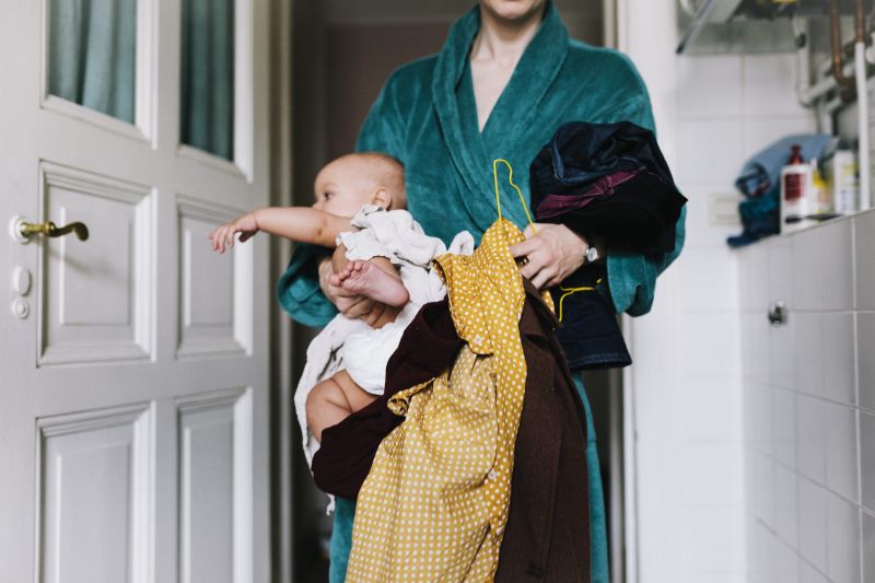 Woman in her bathrobe holding baby and washing