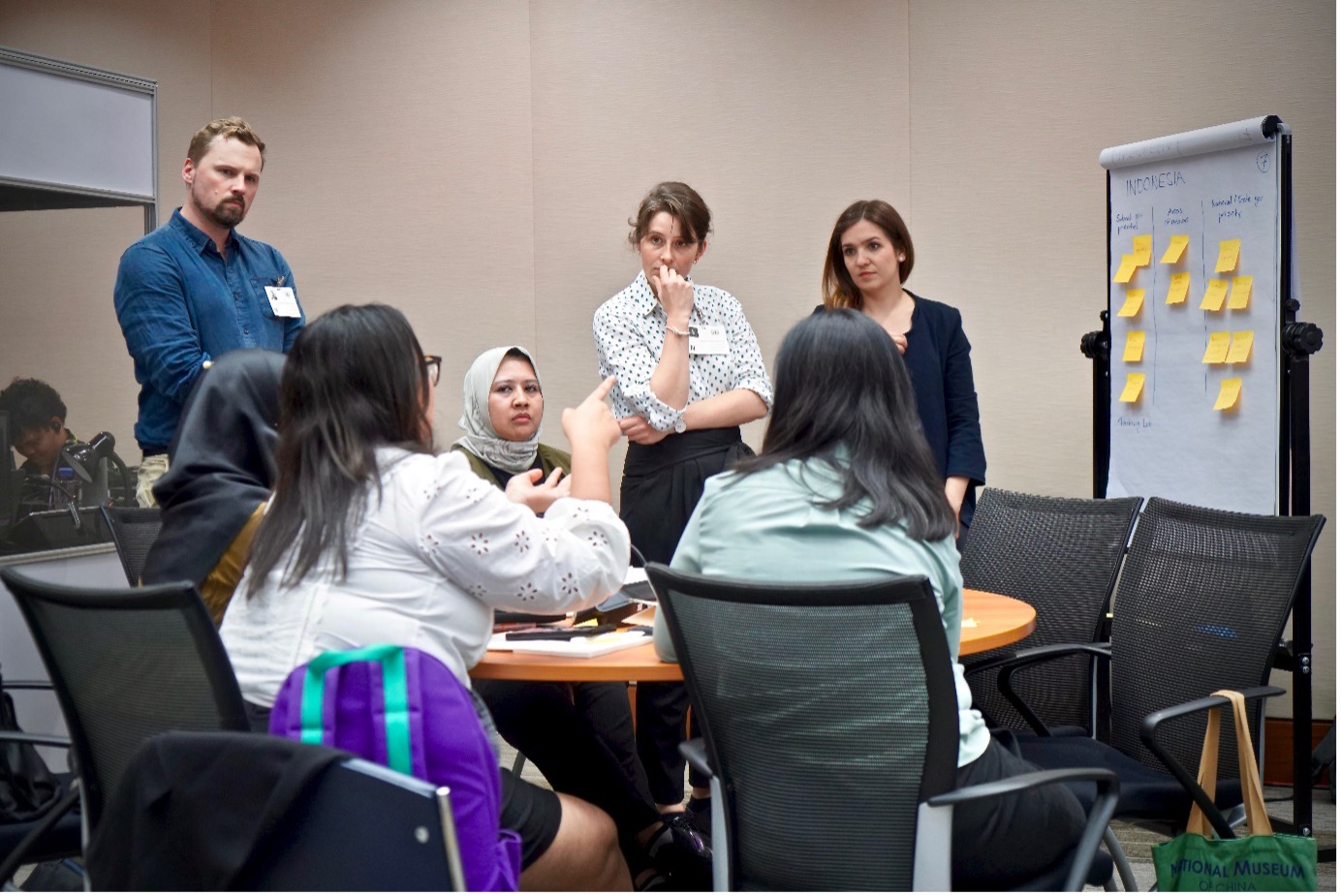 Group surrounded by a table with a whiteboard covered in post it notes