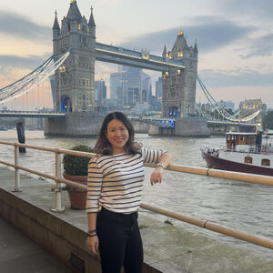 A mentor smiling to camera in front of Tower Bridge, London.
                                class=