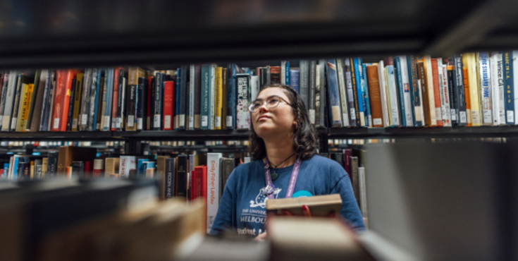 A University of Melbourne librarian sorting books on shelves.