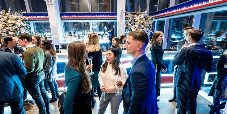 A large group of alumni mingling at a UK Alumni Association event overlooking London.