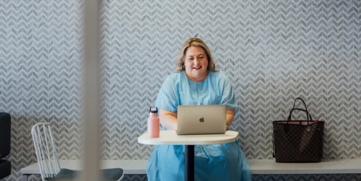 An woman smiling while browsing alumni benefits on her laptop.