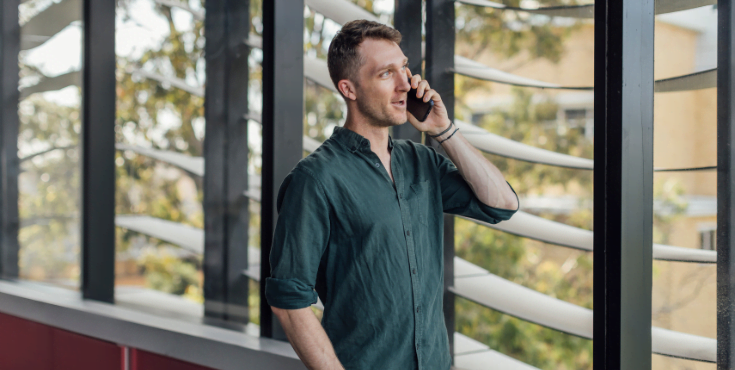 An alum speaking on the phone while looking out a nearby window.