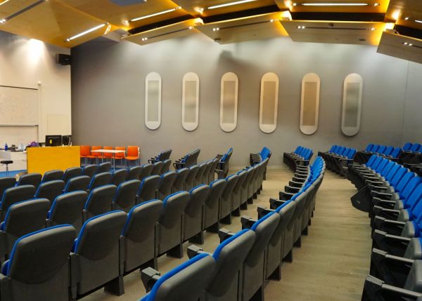 Side view across blue seats in auditorium.