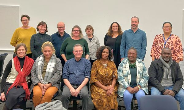 A group people, some sitting and some standing, smiling for the camera