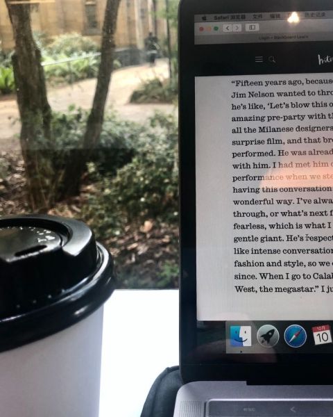 A coffee cup to the left of a laptop