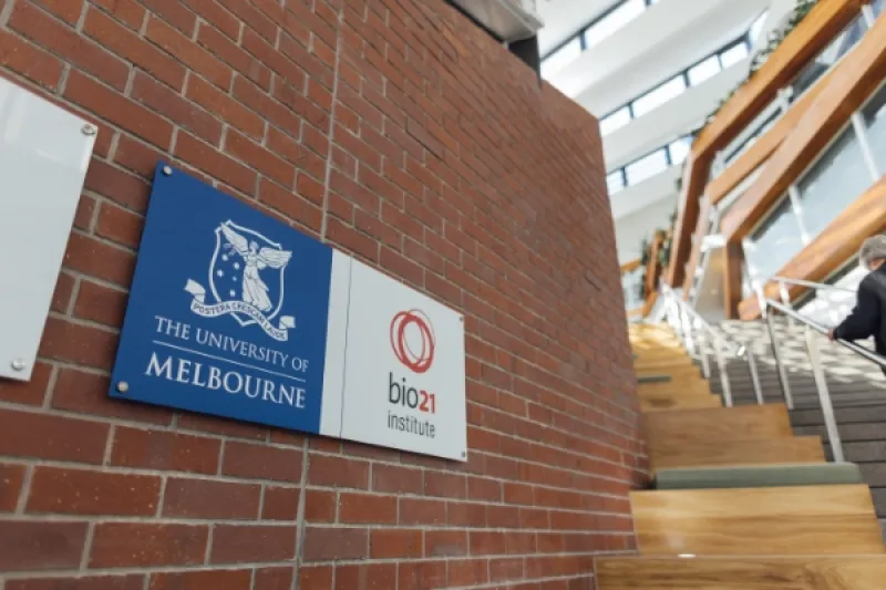 Uni of Melbourne and Bio21 signs on a brick wall at the base of a stairway.