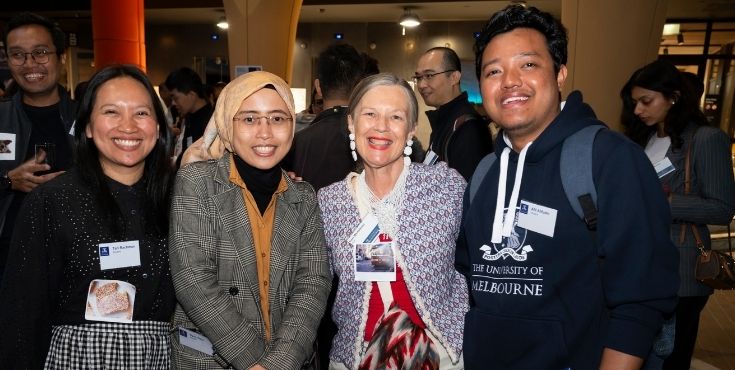 An alum with three international students smiling