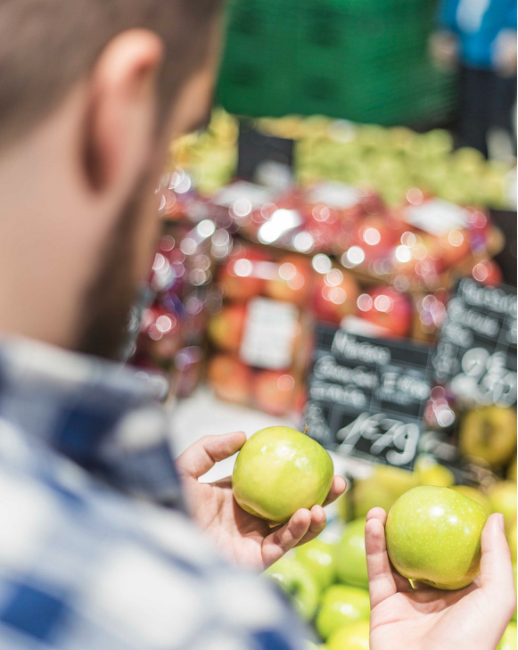 Image of a person holding two apples in his hands trying to choose between them.
