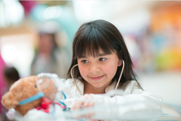 Image of a little girl examining a teddy bear with a stethescope.