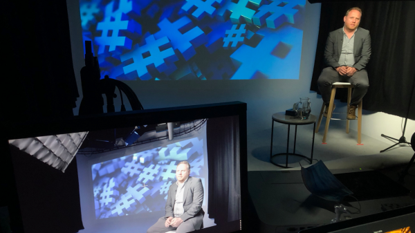 Studio setting with a person on camera, reflected in a teleprompter