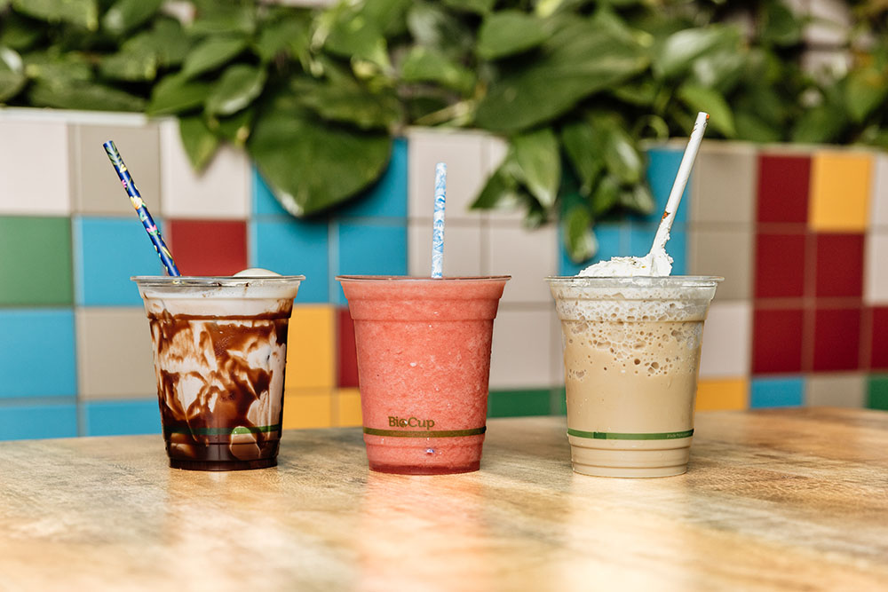 Three drinks lined up on a table: iced chocolate, berry smoothie, iced coffee
