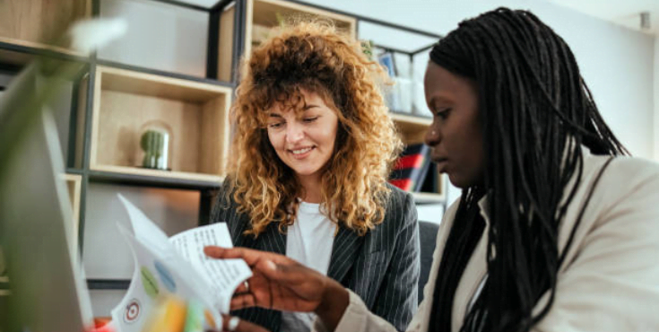 A mentor flicking through a printed assignment paper with her student mentee.