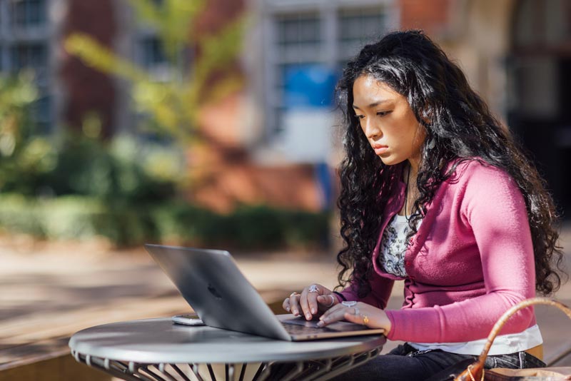 A student studying with a laptop in the grounds of Parkville campus