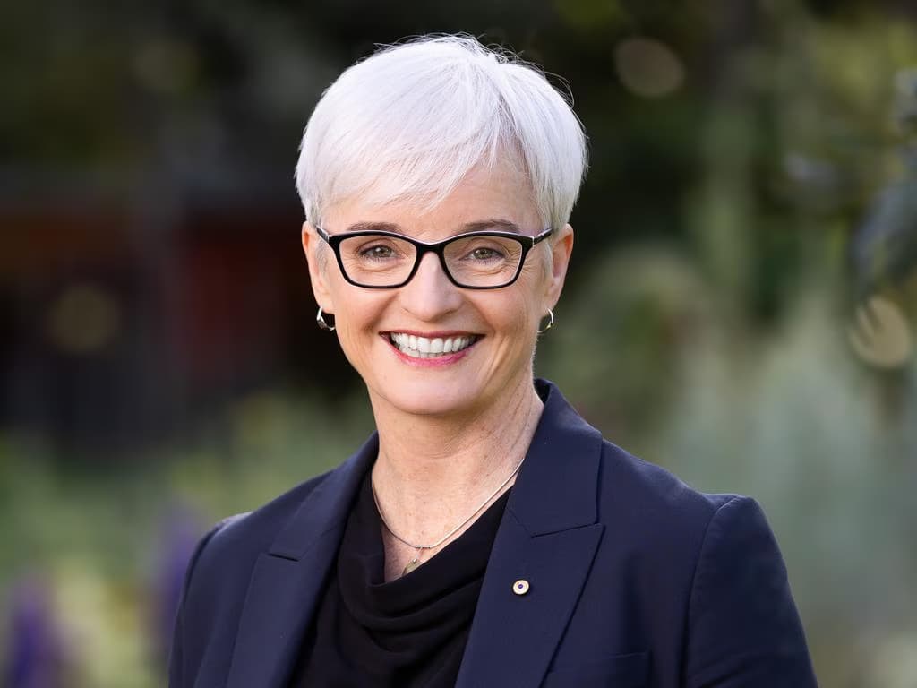 a person with white hair and blue suit smiles