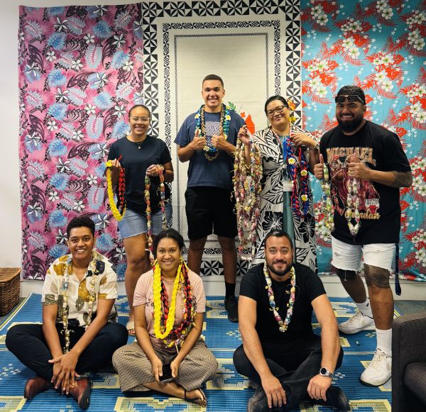 A group of students holding up their finished necklaces. Four standing and three seated.