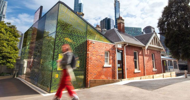 Heritage brick building connected to a modern glass extension, viewed from the street