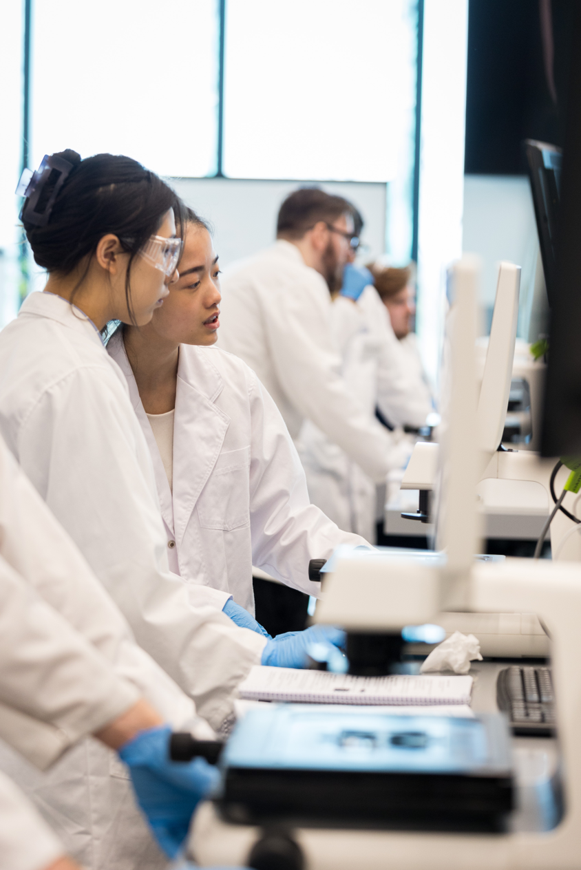 Sample photograph A group of people in lab coats looking at a computer screen.