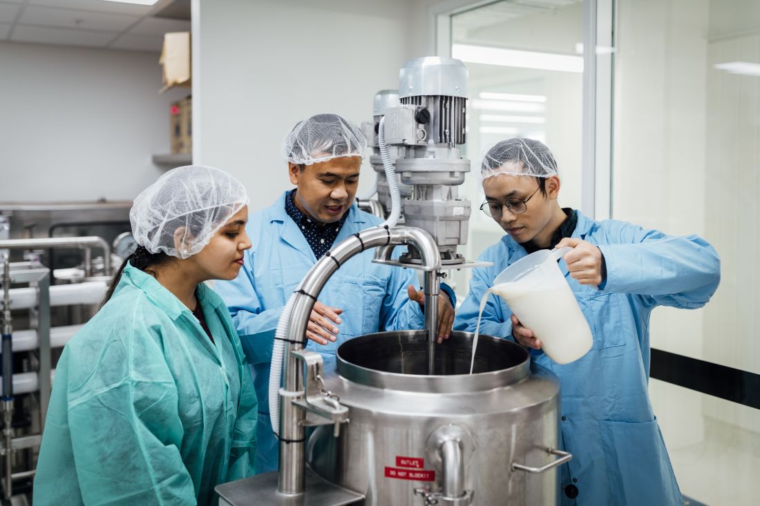 Scientists pouring milk into a vat