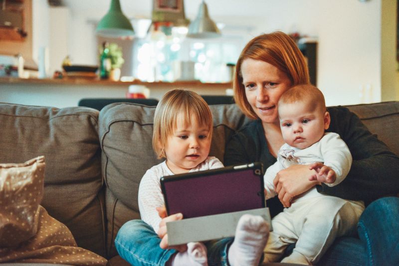 Woman and her two children looking at a tablet on the couch