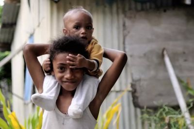 A girl with a toddler sitting on her shoulders