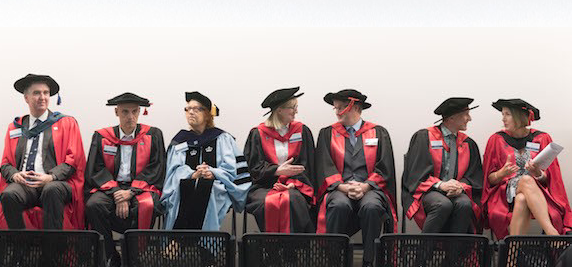 Academics sitting in a row wearing graduation gowns